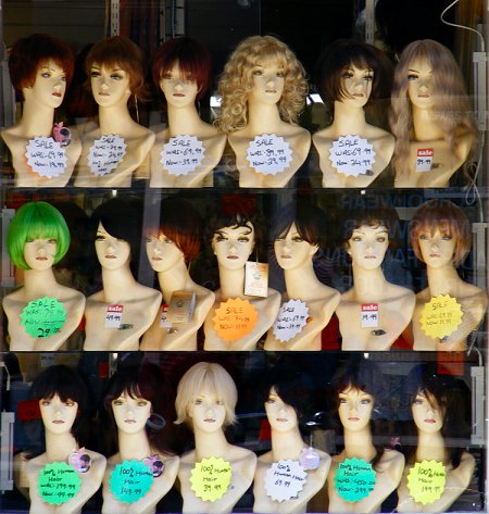 Wigs on 3 shelves in a shop window