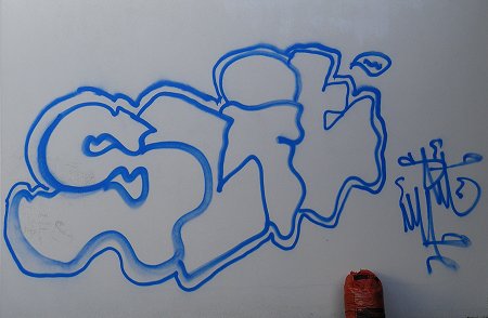 Blue graffiti on a white wall, with orange sack
